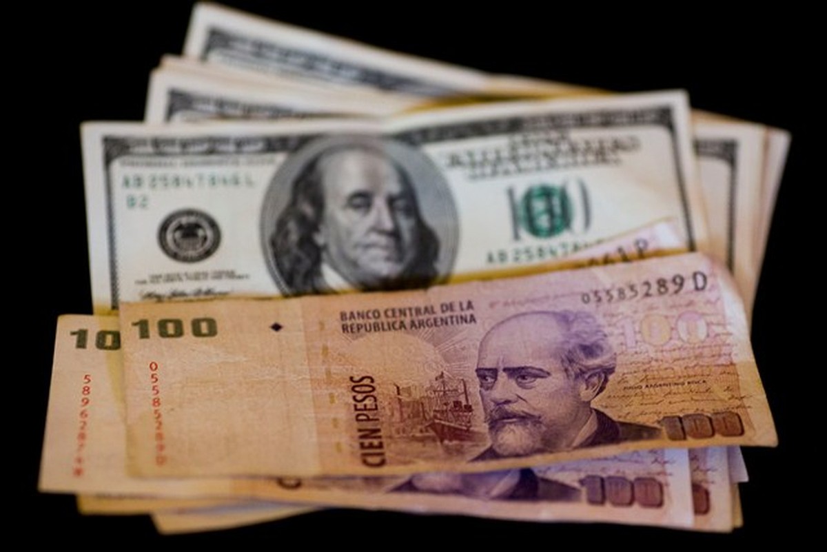 A imagem contém algumas notas de dólar e de peso argentino.