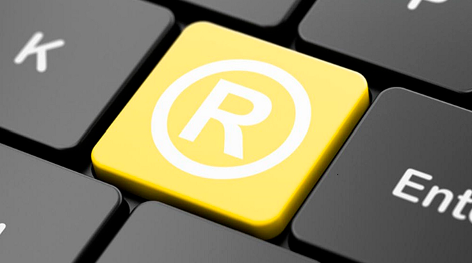 A imagem mostra parte de um teclado de computador destacando uma tecla amarela com o símbolo de marca registrada.